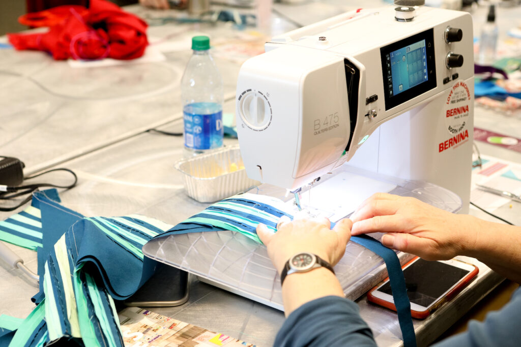 a sewing machine with hands pushing fabric through