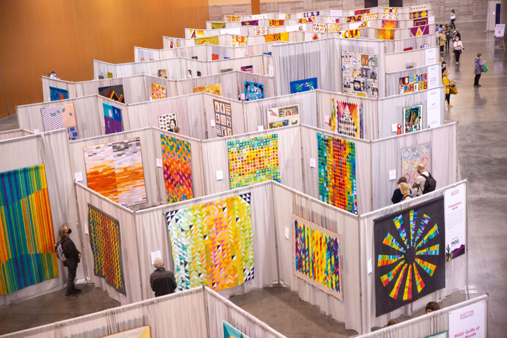 The show floor at QuiltCon Phoenix with many colorful quilts. 