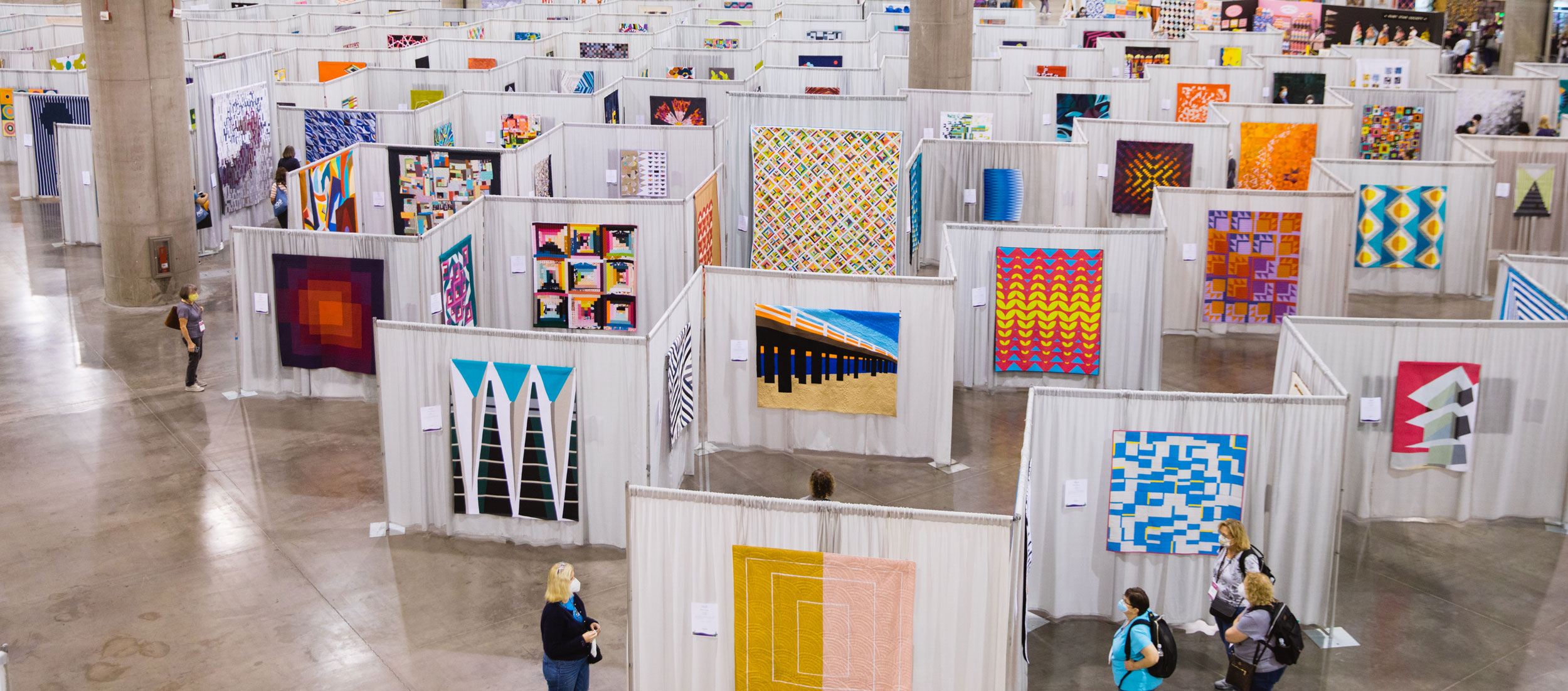 the quiltcon show floor with rows of drape and colorful quilts